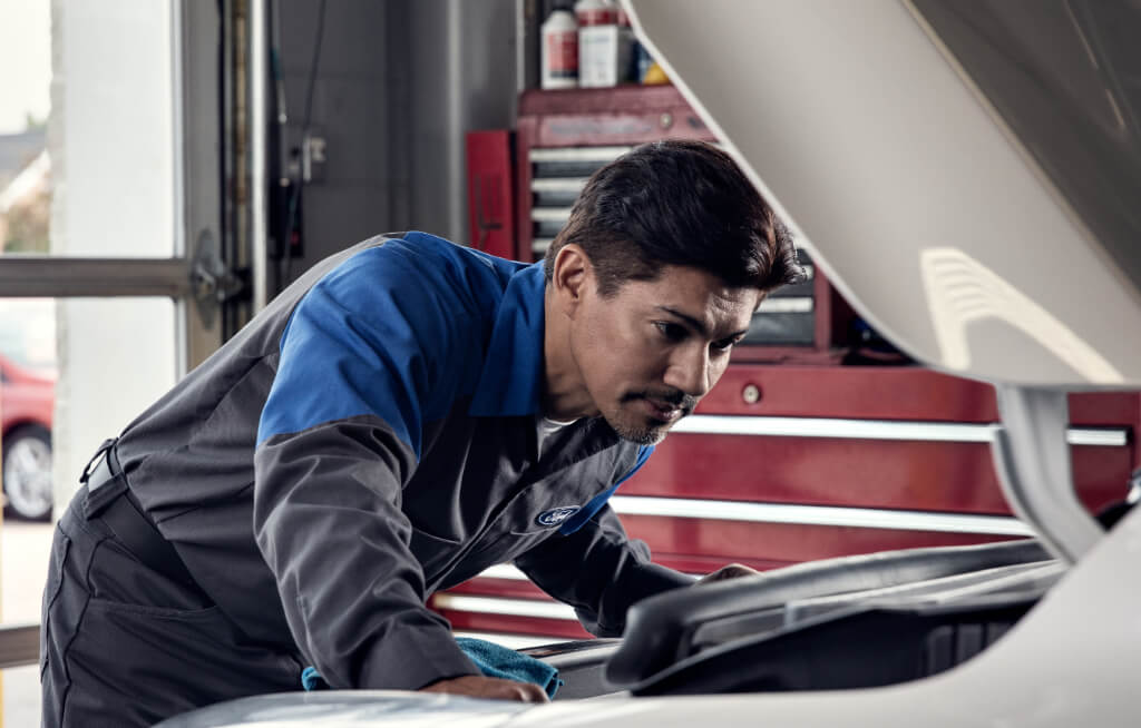Mecânico verificando o motor de um veículo Ford