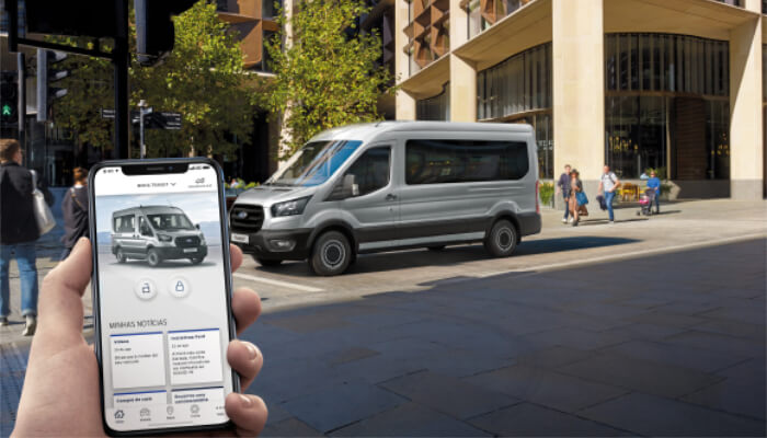 Ford Transit Minibus ao fundo e homem segurando celular com o app Ford