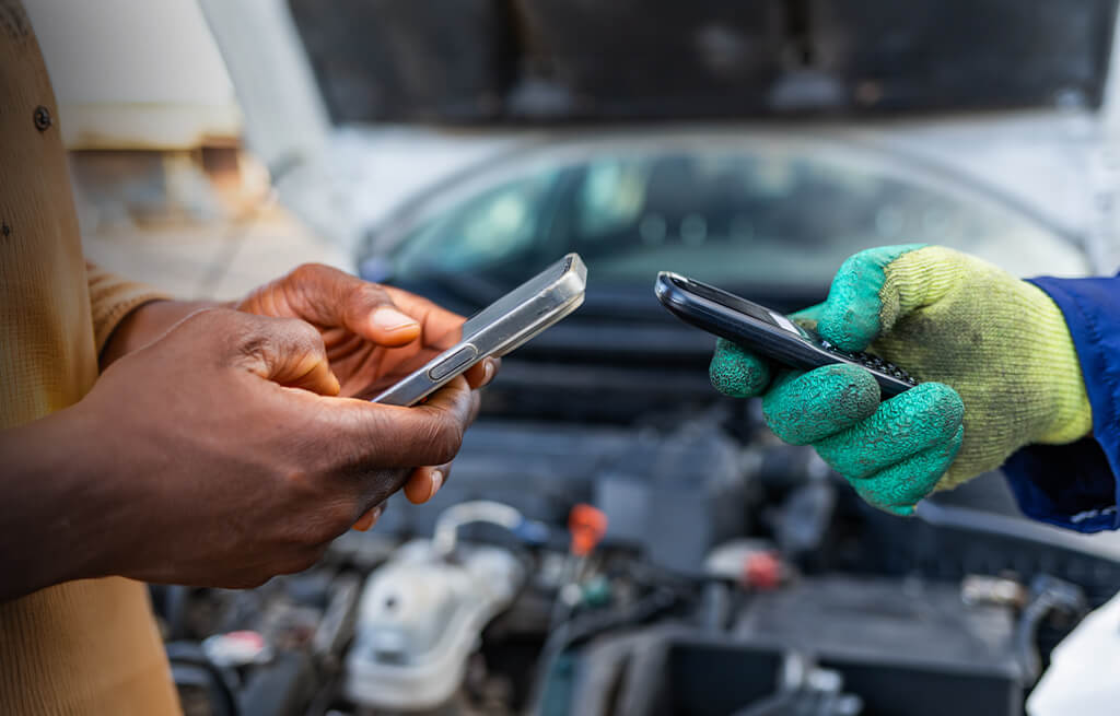 Mecânico e cliente segurando seus celulares