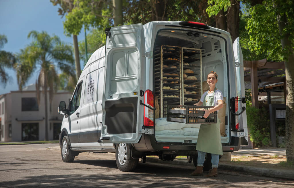 Mulher retirando pães de uma Ford Transit Furgão utilizada para panificação