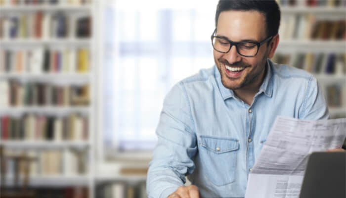 Financiamentos Adicionais Homem segurando um contrato e sorrindo