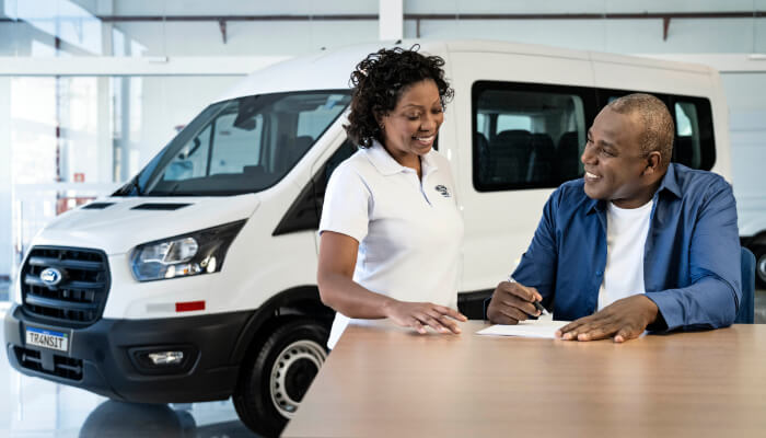Financiamento Homem e mulher sorrindo e assinando um contrato e Ford Transit Minibus