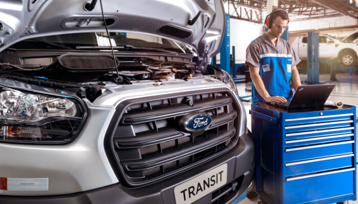 Ford Transit em manutenção na oficina e mecânico operando computador