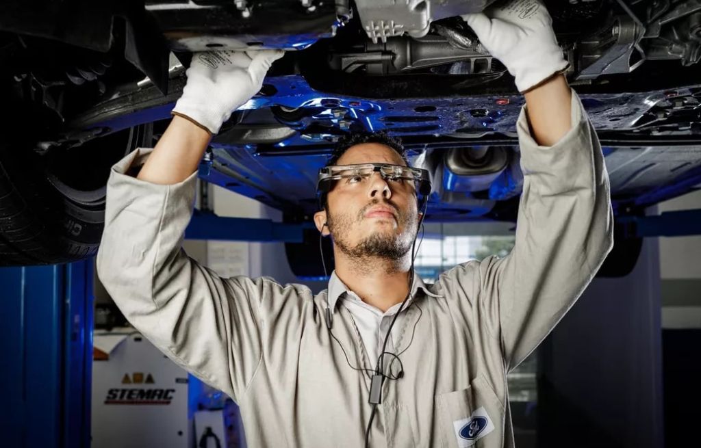 Homem consertando a parte de baixo de um carro