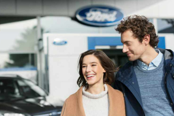 Lächelnde Kundin und Kunde verlassen Ford Garage