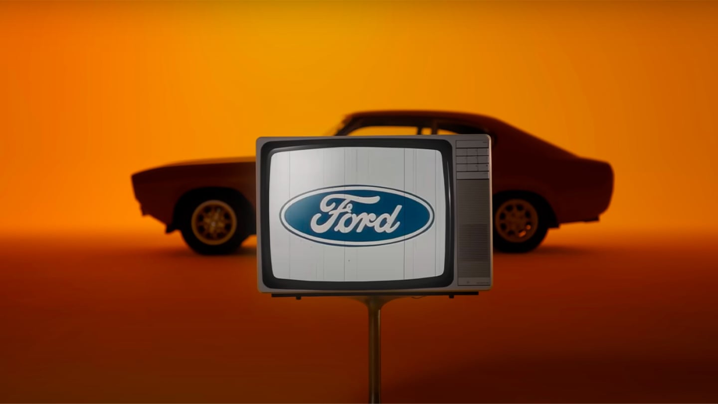 Ford Capri d'epoca su sfondo arancione con logo Ford
