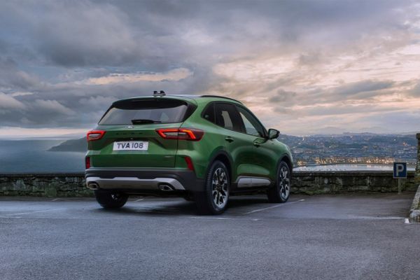 Grüner Ford Kuga fährt auf Strasse vor Meer
