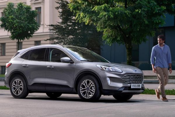 Un homme marche le long de la route devant la Ford Kuga
