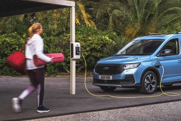 Tourneo Connect Recharge Une femme porte un tapis de yoga près d'un véhicule Ford bleu