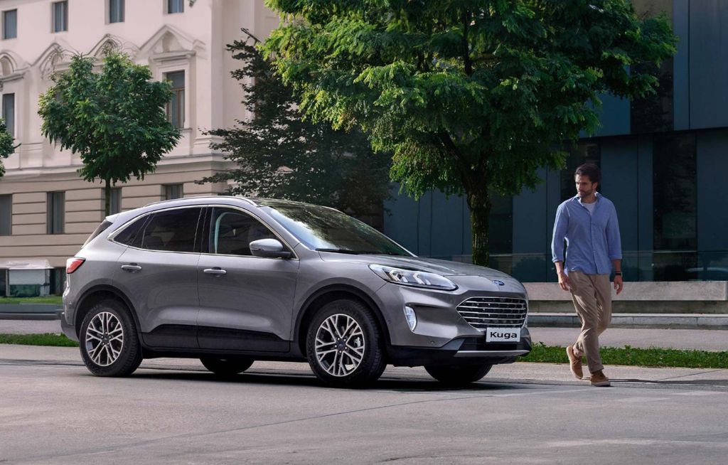 Homme marchant près d'une Ford Kuga grise